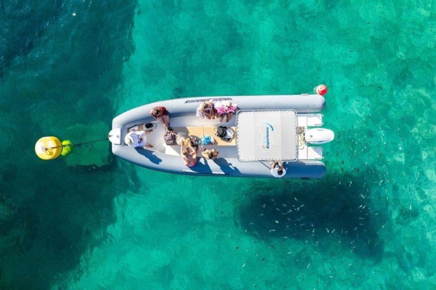 Un bote inflable con gente navegando en un mar turquesa y transparente. 3