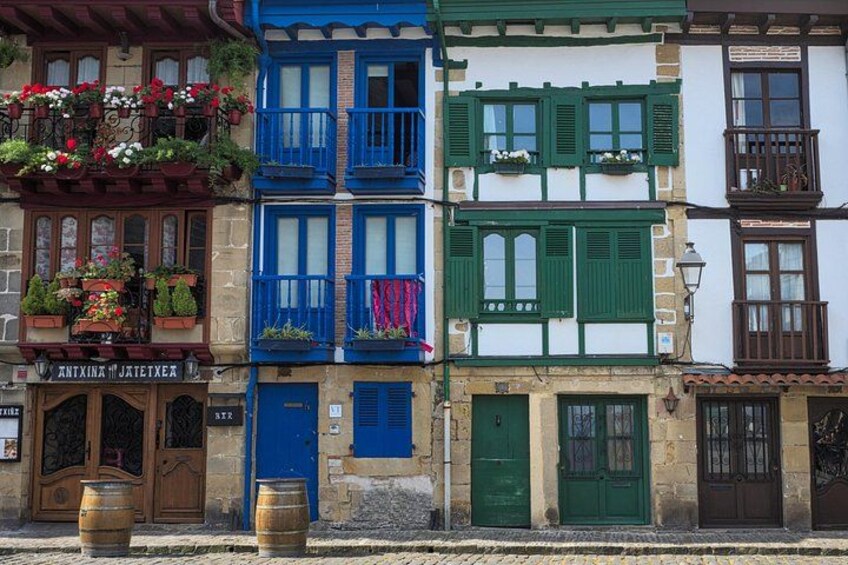 Una fila di edifici colorati con balconi, porte in legno e fioriere. 1