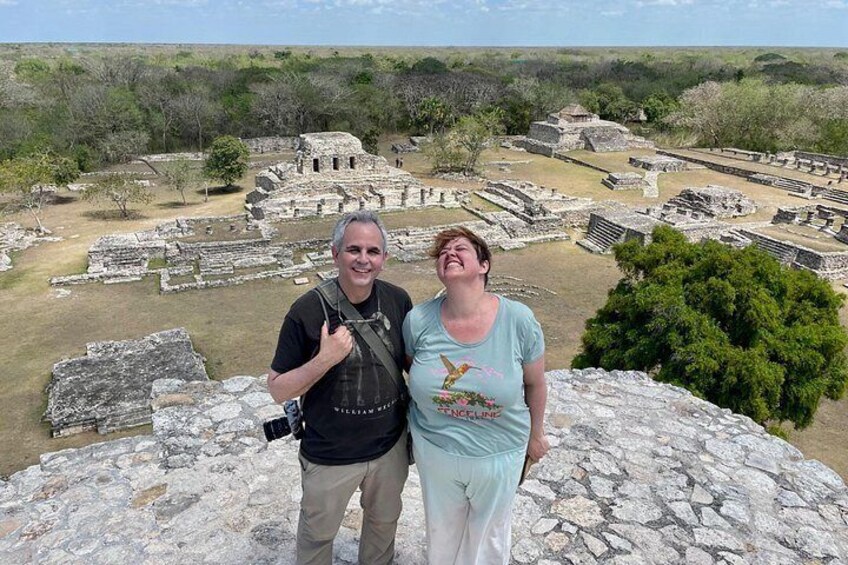 Two people standing on a rocky outcrop overlooking ancient ruins. 4