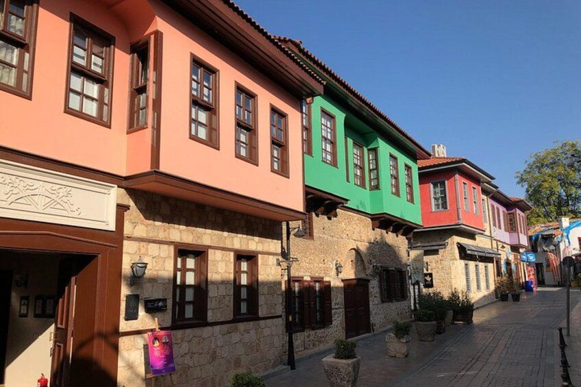 A street with colorful buildings, stone walls, and potted plants. 5
