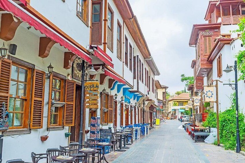 A narrow street lined with traditional buildings, outdoor seating, and a variety of shops. 2