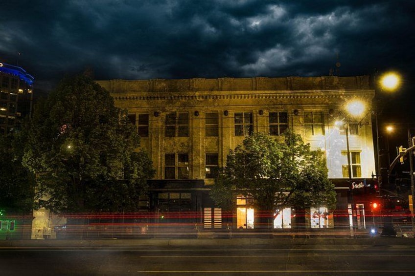 Un bâtiment historique aux fenêtres illuminées, avec une rue au premier plan. 4