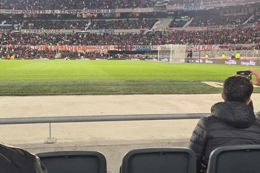 A stadium with spectators, a soccer field, and advertisements. 5