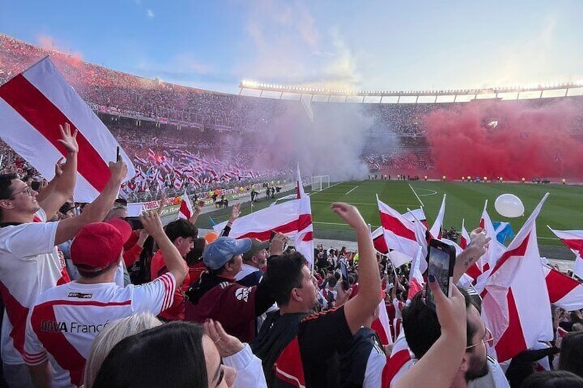 A stadium filled with fans waving flags and cheering. 1