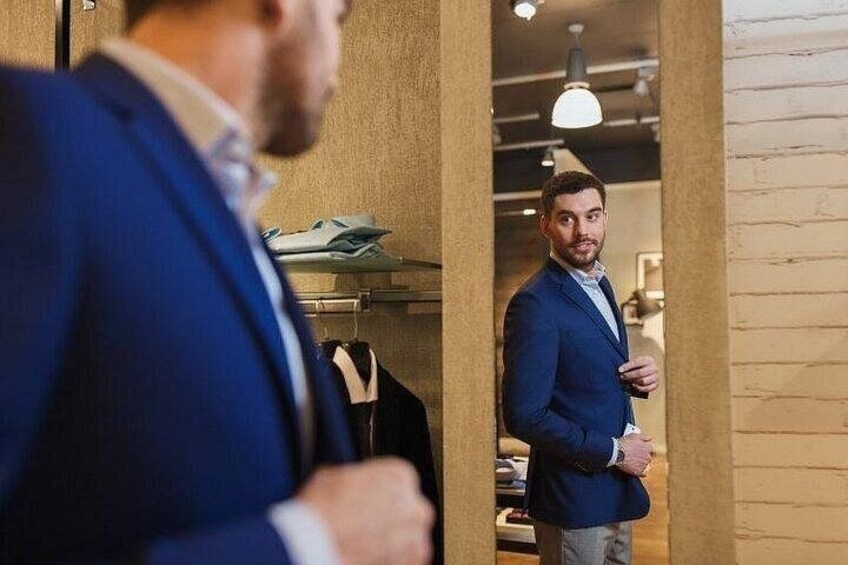 Een man in een blauw pak staat in een kamer met houten wanden en een hanglamp. 5