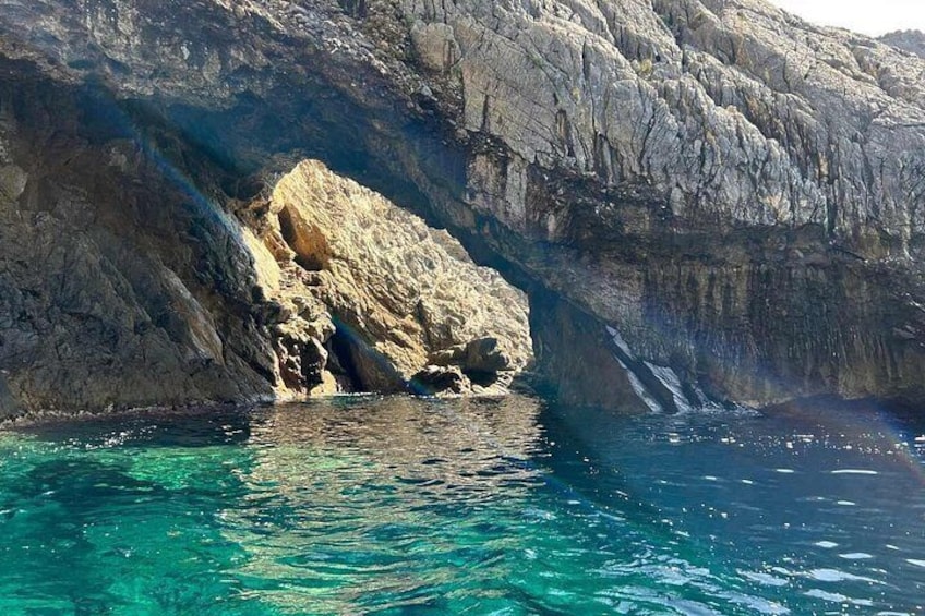 A rocky coastline with clear blue water and a waterfall. 3