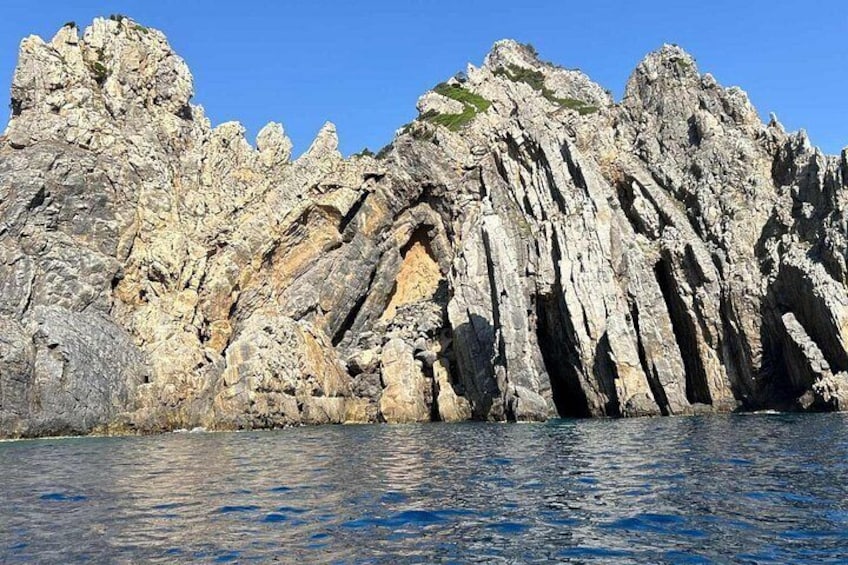 A rocky coastline with jagged cliffs and clear blue water. 4