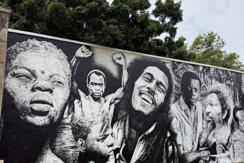 A mural with multiple figures, trees, and a building in the background. 2