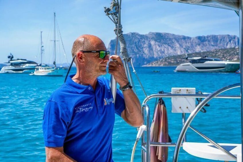 Un uomo con una camicia blu in piedi su una barca, aggrappato a una struttura metallica. 2