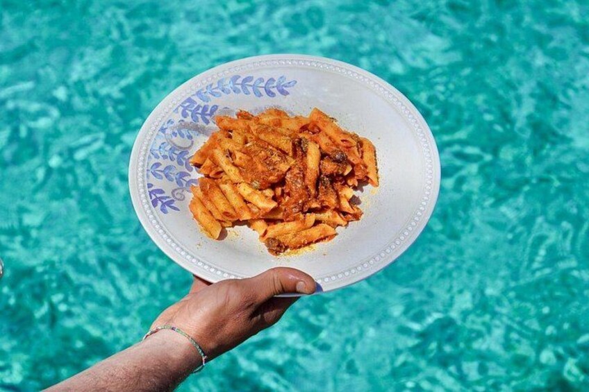 A hand holding a plate with food over a pool. 4