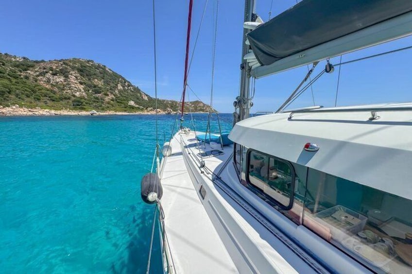 Una barca a vela su acque turchesi con una costa rocciosa sullo sfondo. 4