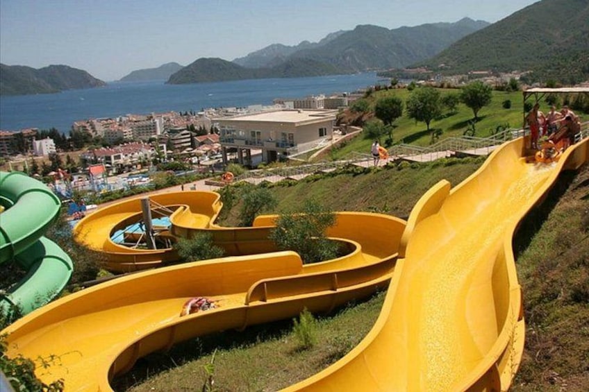 Een waterpark met verschillende glijbanen en uitzicht op de zee en bergen op de achtergrond. 5