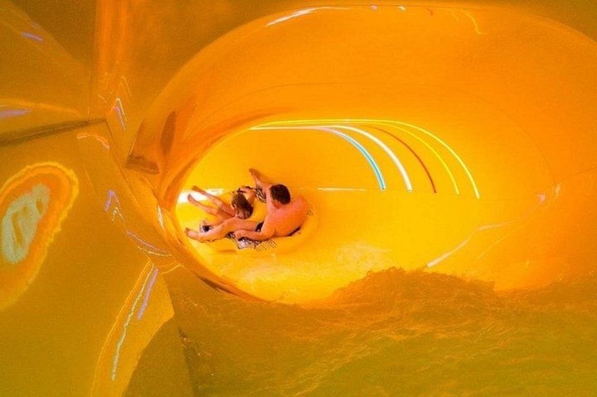 Een grote, oranje glijbaan met mensen die naar beneden glijden. 2
