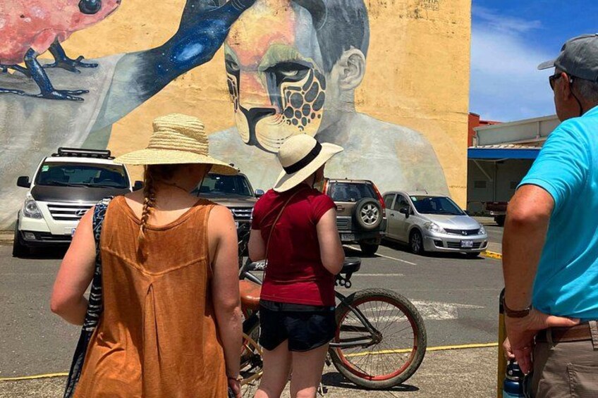 A mural on a building, a bicycle, and parked cars. 4
