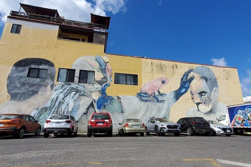 A mural on a building with cars parked in front. 2