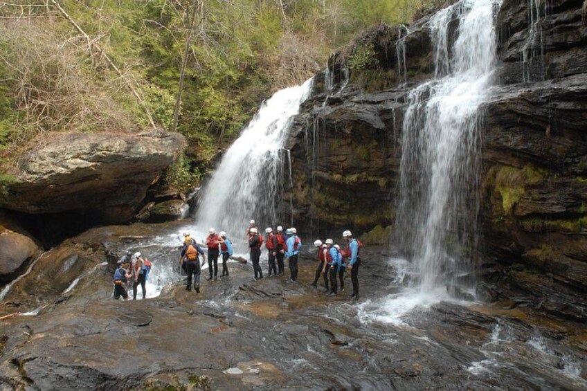 Un grupo de excursionistas parado sobre terreno rocoso con una cascada al fondo. 2
