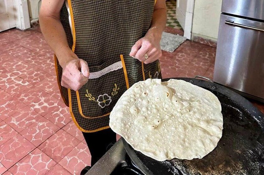 Una persona cocinando un pan plano en una estufa. 4