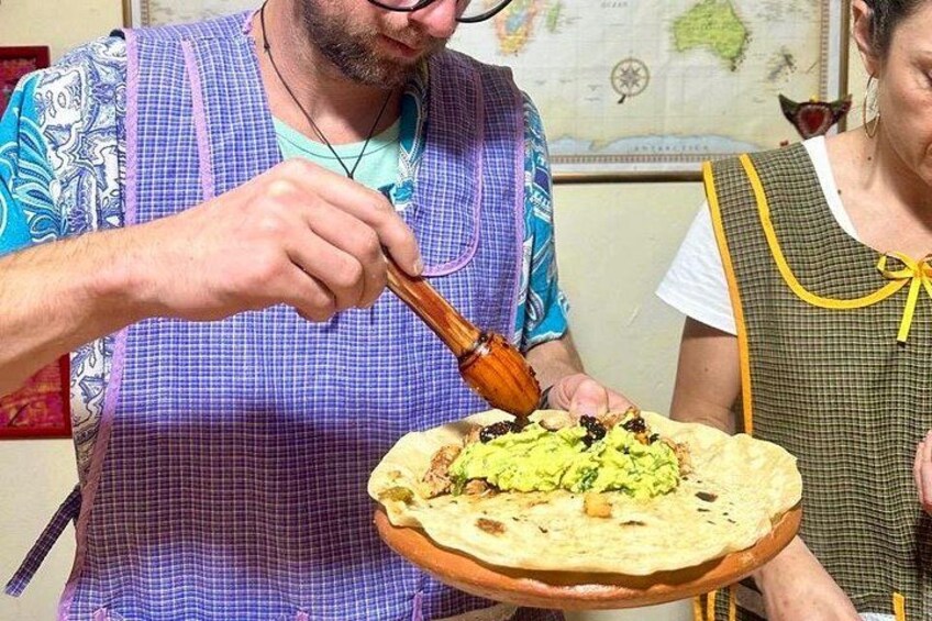 Una persona preparando un plato con pan plano, una cuchara de madera y salsa verde. 5