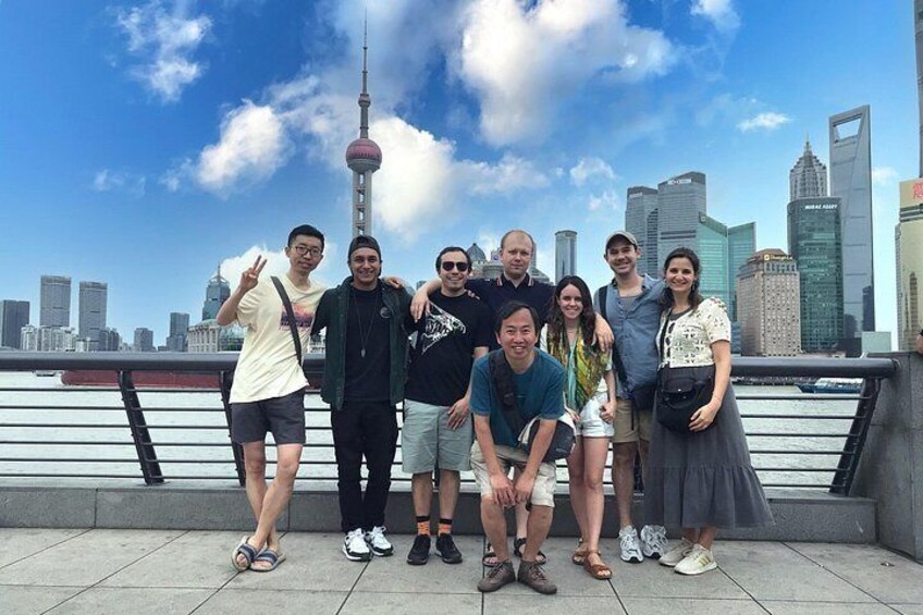 A group of people posing in front of a city skyline with a prominent tower. 1