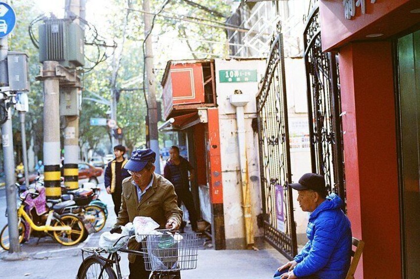 A street scene with a man on a bicycle, a man sitting on a bench, and a yellow bicycle parked on the side. 5