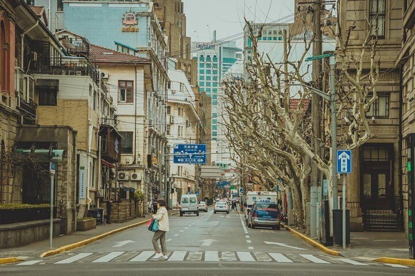 A street with buildings, a pedestrian crossing, and a blue directional sign. 3