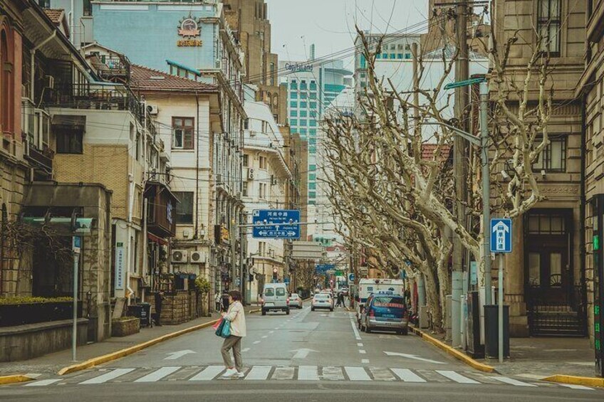 A street with buildings, a pedestrian crossing, and a blue sign. 3