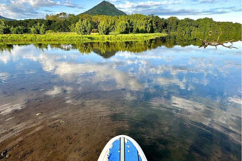 Un lac paisible, avec un bateau au premier plan, entouré d’une végétation luxuriante et avec une montagne en arrière-plan. 4