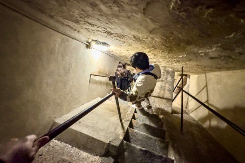 En person som går nerför en mörk stentrappa i en grotta. 5