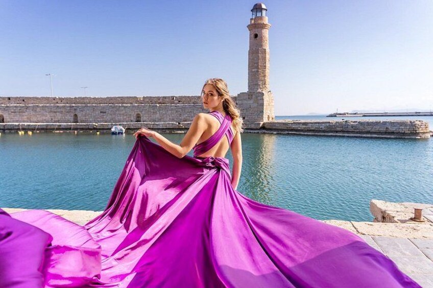 A person in a purple dress by a waterfront with a lighthouse in the background. 2