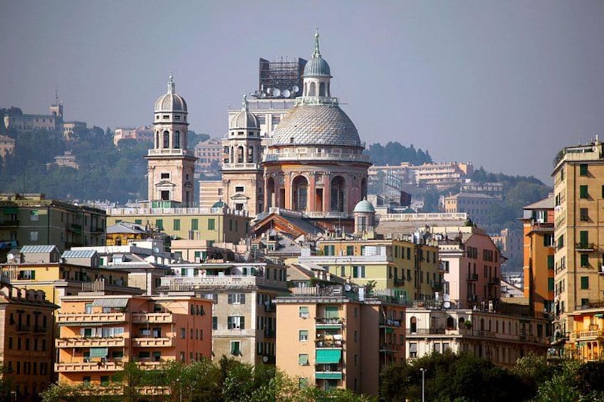A historic cityscape with prominent domed buildings and a hill in the background. 2