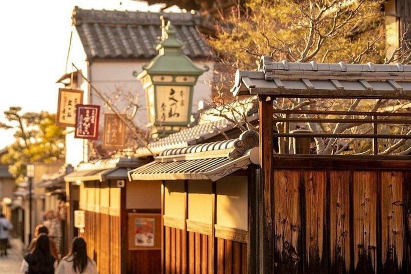 Eine traditionelle japanische Straße mit Holzbauten, einem grünen Laternen und einem Holztor. 5