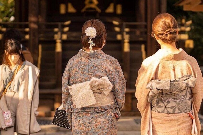 Drei Personen in traditioneller japanischer Kleidung stehen vor einem Gebäude mit Holzbauweise und Steinfundament. 4