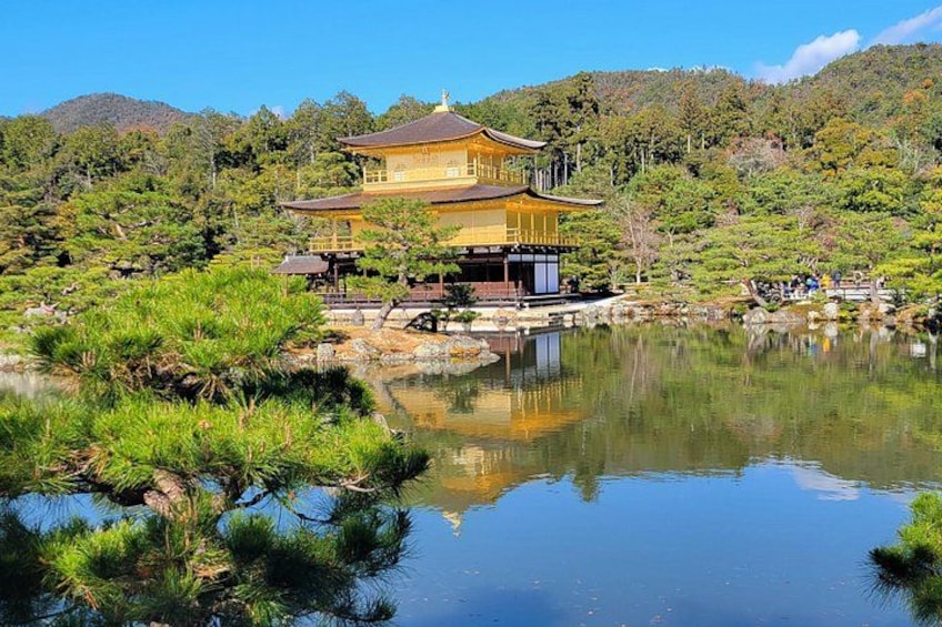 Ein traditionelles japanisches Gebäude mit goldenem Dach, umgeben von einem friedlichen Teich und üppiger Vegetation. 1