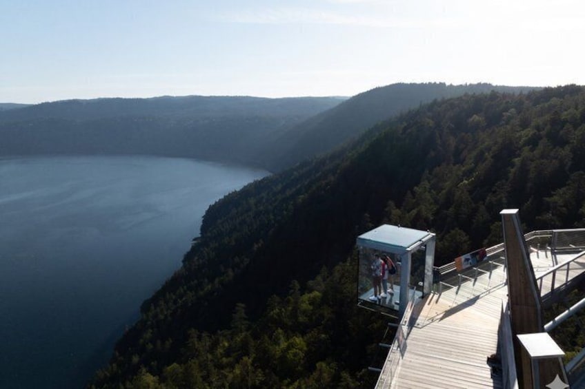 A wooden observation deck overlooking a lake with a forested mountain backdrop. 2