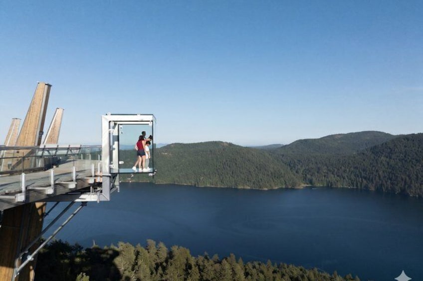 A platform extending over a lake with a forested mountain range in the background. 3