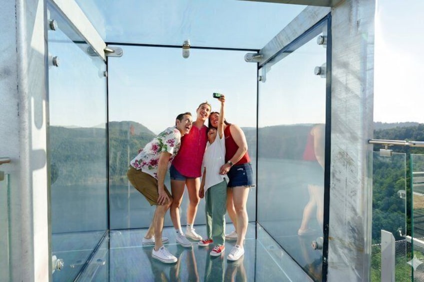 Three people inside a glass enclosure with a mountainous landscape in the background. 5
