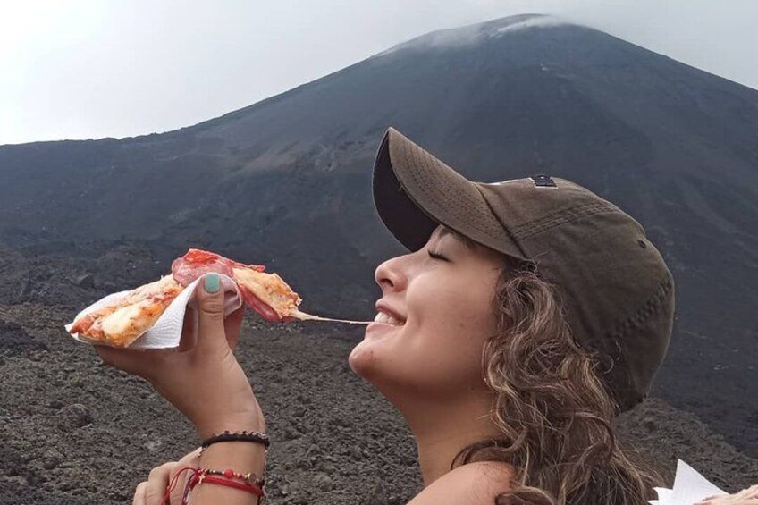 Une personne mangeant une pizza avec un volcan en arrière-plan. 1