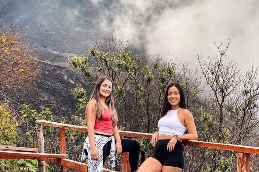 Twee personen zitten op een houten bankje, met een bergachtig landschap op de achtergrond. 2