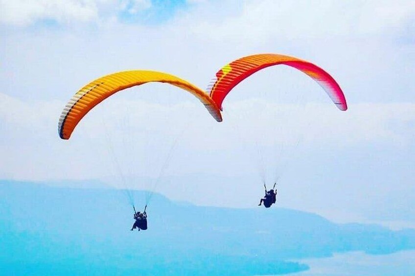 Dos parapentistas con paracaídas de colores volando sobre un paisaje montañoso. 1