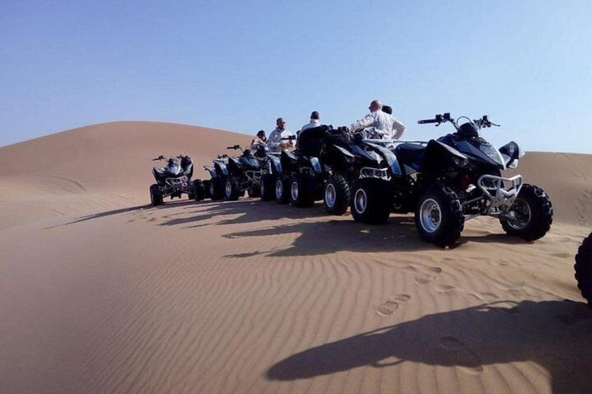 A group of people on ATVs in a desert with sand dunes. 4
