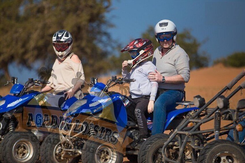 Three people on an ATV with 'AGADIES' written on it. 5