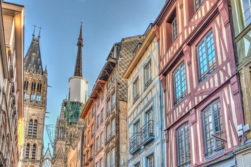 Una calle con edificios tradicionales de entramado de madera y una iglesia con aguja. 4