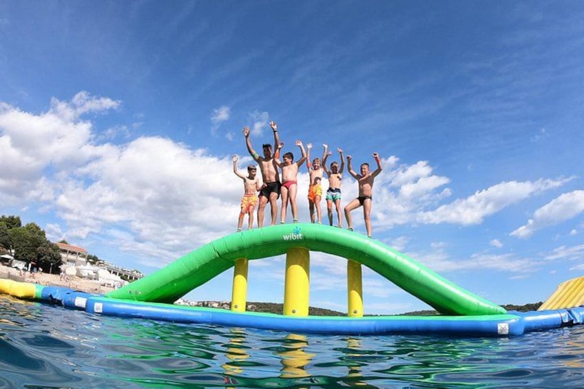 A group of people on a green inflatable water slide. 5