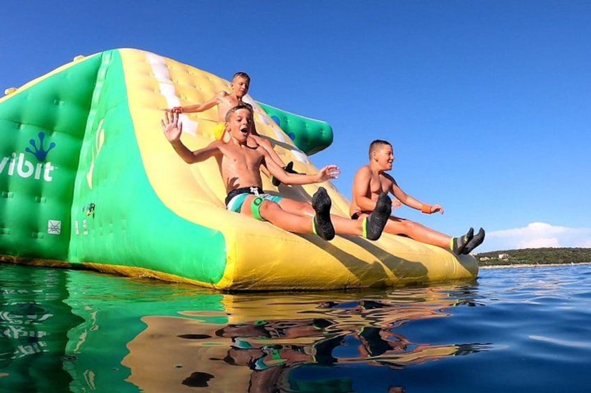 A green and yellow inflatable water slide in a body of water with clear skies. 2