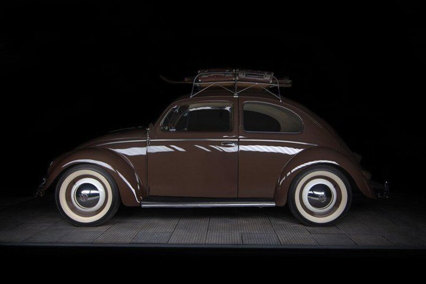 Ein braunes Vintage-Auto mit weißen Reifen, einer Dachbox und einem klassischen Design. 2