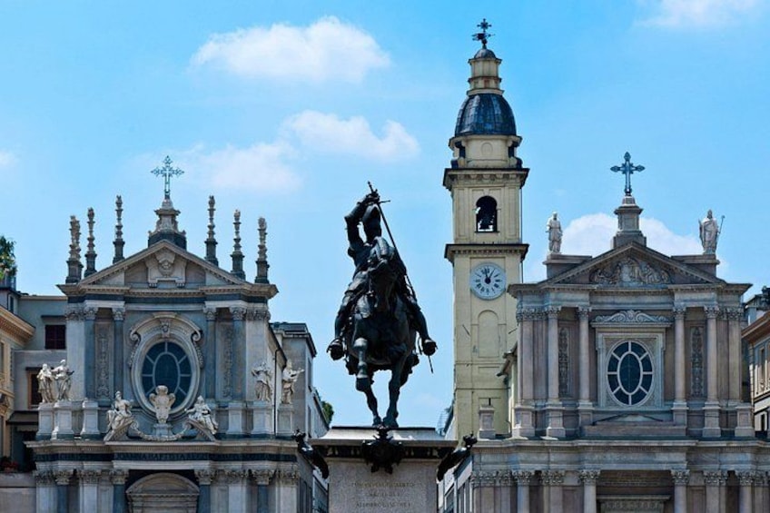 Un edificio histórico con una torre del reloj, estatuas y una estatua central de un jinete. 2