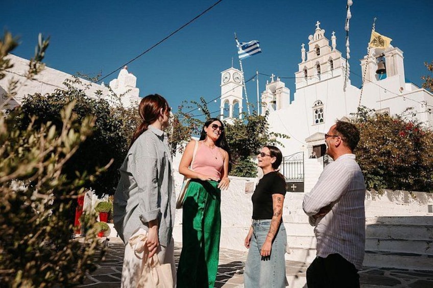 Un grupo de personas de pie frente a una iglesia blanca con detalles en azul y dorado. 5