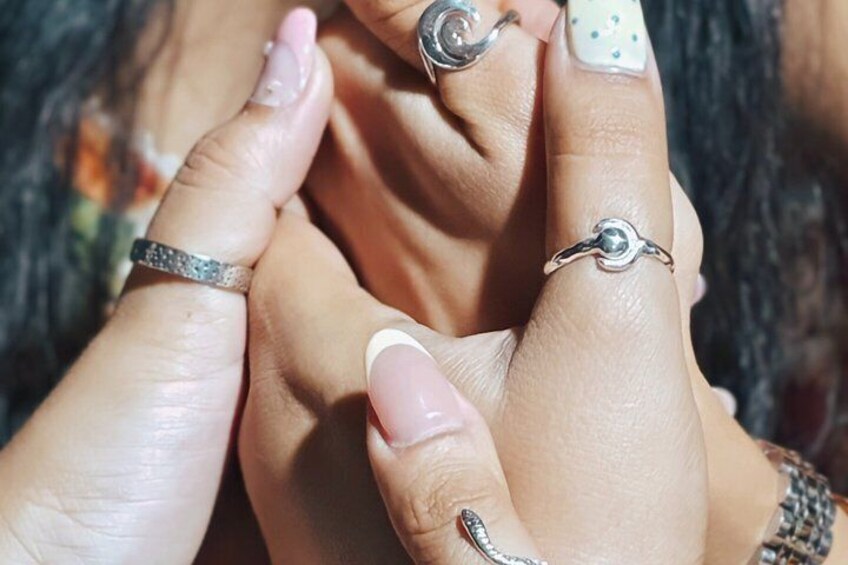 Et nærbillede af hænder med forskellige ringe og et armbånd. 2
