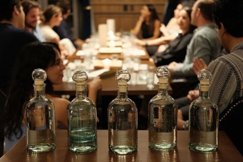 A group of people seated around a table with several empty bottles in front of them. 1