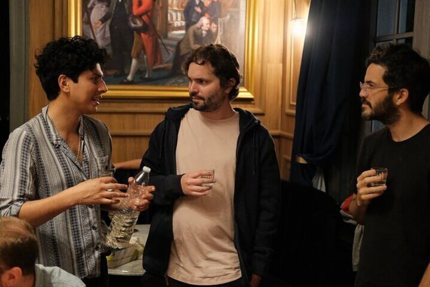 Three people conversing in an indoor setting with a painting in the background. 4